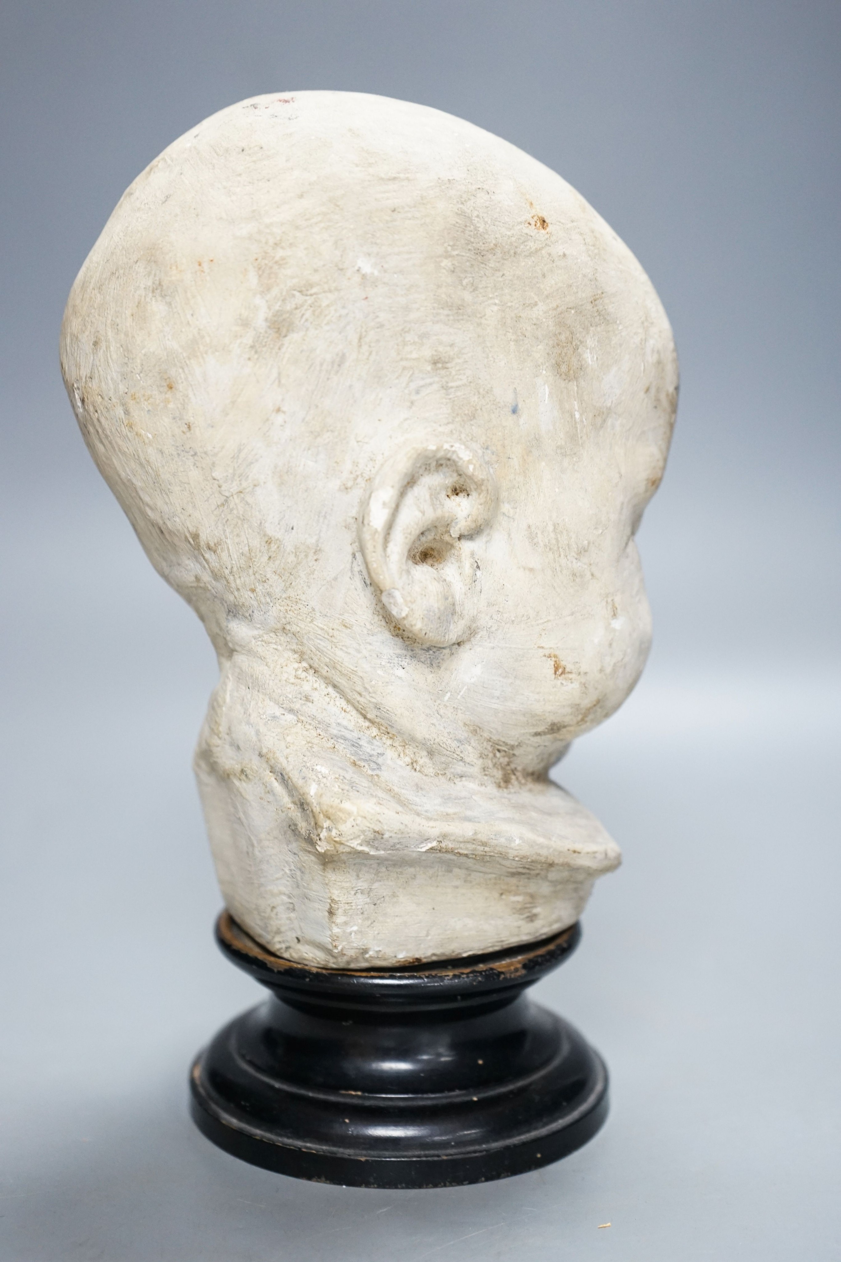 A 19th century memento mori plaster bust of an infant, on ebonised socle 22cm